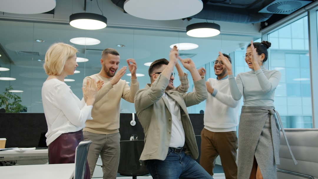 Happy people employees are dancing at corporate party enjoying music having fun clapping hands in shared workspace office. Relaxation and dance concept.